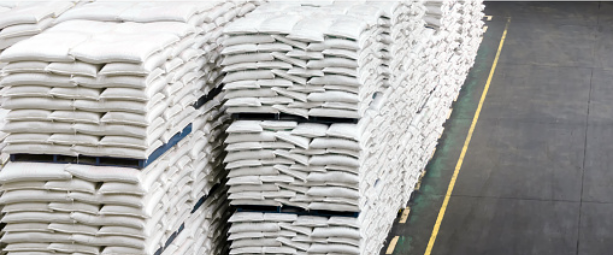 white 50 pound bags of fertilizer are stacked on pallets in a warehouse
